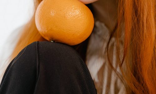 image montrant une femme maintenant une orange avec son menton